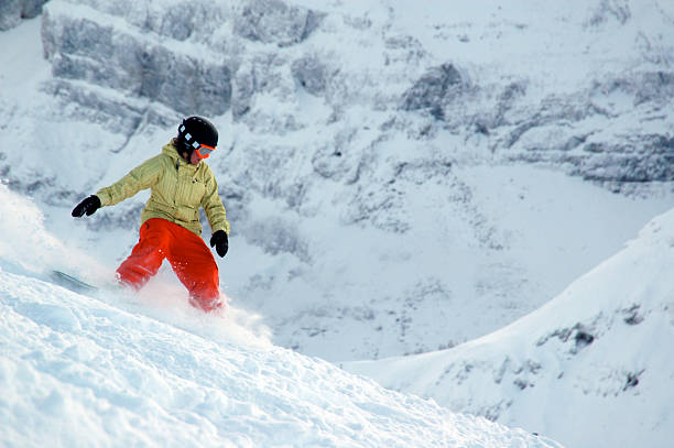 istock Snowboarder in orange and yellow rides through powder 178982757