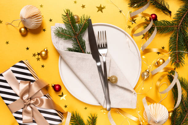 istock Festive table setting plate, gift and Christmas  decor on yellow background, invitation dinner birthday party anniversary. top view 1789834987