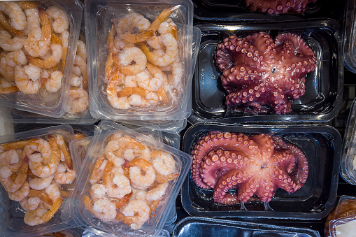 Octopus and shrimps precooked in vacuum-sealed trays for sous vide cooking for sale in supermarket refrigerated counters