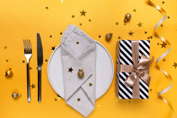 istock Festive table setting plate, gift and Christmas  decor on yellow background, invitation dinner birthday party anniversary. top view 1789837143