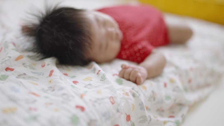 Close-up of a month-old baby boy sleeping in a cozy bed in parents' bedroom.