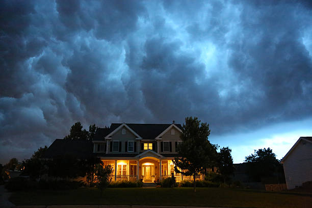 House in bad summer thunderstorm A well appointed house is lit up while a large thunderstorm moves in overhead. Ample copy space above. household insurance stock pictures, royalty-free photos & images