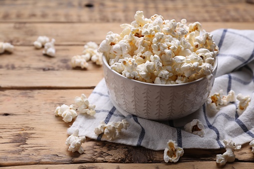 Stock photo of bucket of popcorn in cinema / movie theatre, movie snack. Caramelised / caramel toffee popcorn as movie snack food in paper cups with empty red seats in foreground.