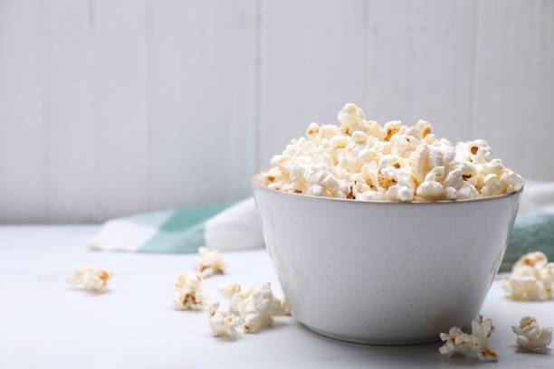 istock Bowl of tasty popcorn on white table, space for text 1789887491