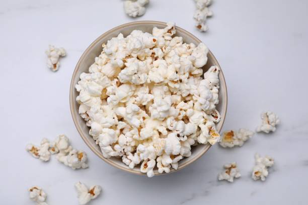istock Bowl of tasty popcorn on white marble table, flat lay 1789887509