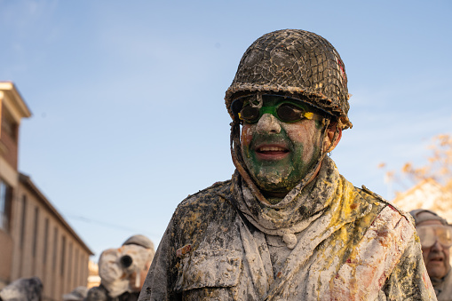 Ibi, Spain - December 28, 2022: Portrait of a man covered in flour and eggs dressed as a soldier in the middle of a fun battle at a traditional winter festival called 'Els Enfarinats'