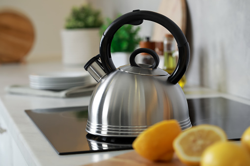 Stylish kettle with whistle on cooktop in kitchen
