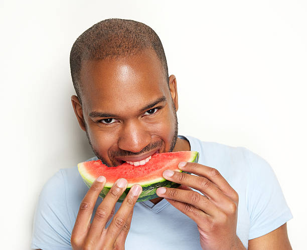 istock Young man smiling and eating delicious watermelon 178988981