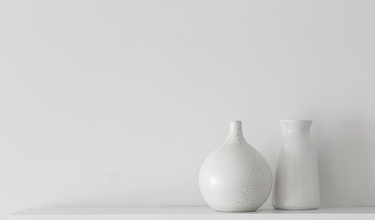 white ceramic vases on wooden shelf on white wall