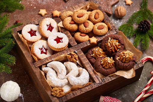 Box with variety of Christmas cookies: linzer cookies with strawberry jam, crescents with walnuts and sugar powder, almond cookies, chocolate cookies with Dulce de leche condensed milk.