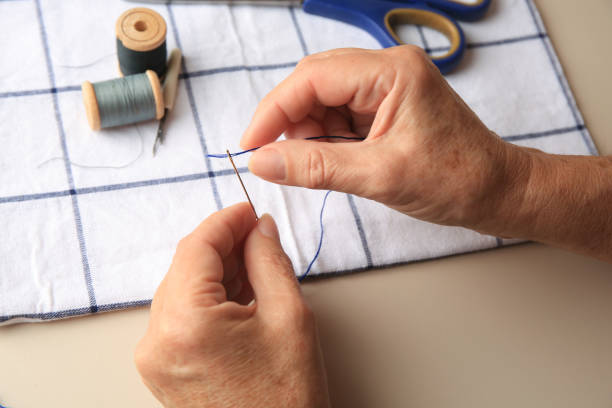 istock Closeup view of woman threading needle at beige table 1789913772