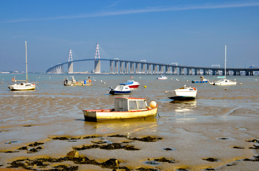 Small boats at low tide and the big bridge of Saint Nazaire at Saint Brevin les Pins in Pays de la Loire region in western France