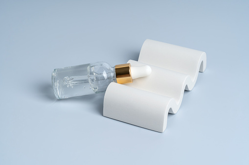 A transparent serum or gel in a dropper bottle on a white concret podium, product presentation, marketing showing
