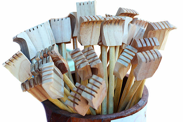 A group of natural wooden kitchen utensils photographed from a side angle on a yellow background.