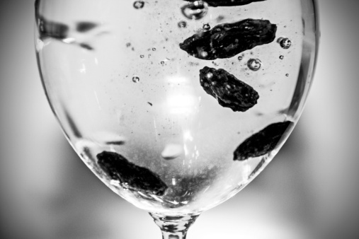 Raisins dipped in a glass full of sparkling water