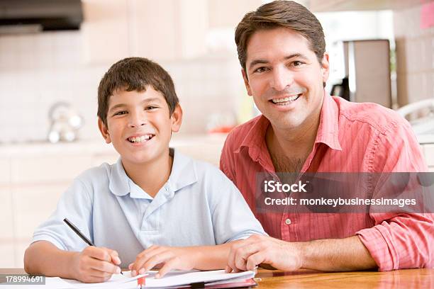 Man Helping Young Boy In Kitchen Doing Homework Stock Photo - Download Image Now - Approaching, People, Latin Script