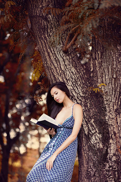 Girl reading a book in the park stock photo