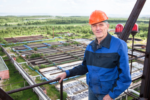 Smiling Caucasian worker standing for high altitude platform. Copyspace. Water treatment plant