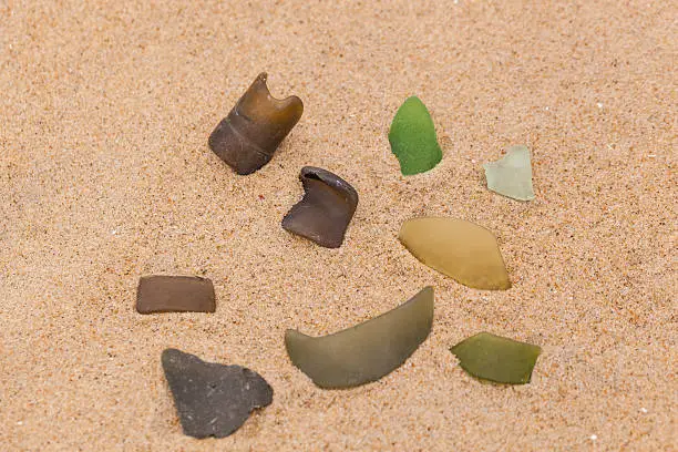 Seaglass washed ashore from the Atlantic Ocean is photographed on the beach in the sand.  Brown, Green, Light Green seaglass is imaged.