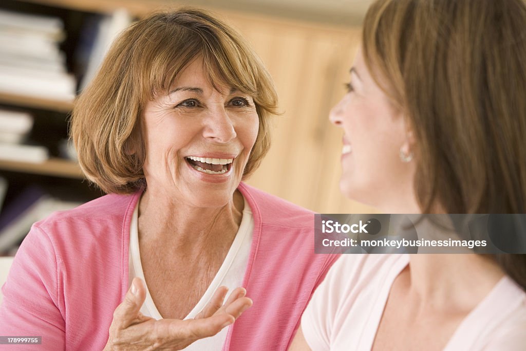 Dos mujeres en la sala de estar y sonriente hablando - Foto de stock de 30-39 años libre de derechos
