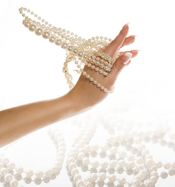 Male human hand holding strands of cultured Japanese Akoya pearls.