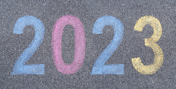 Start the New year 2023 stenciled in pavement paint on the asphalt, start trip concept. Celebration journey into the New Year numbers