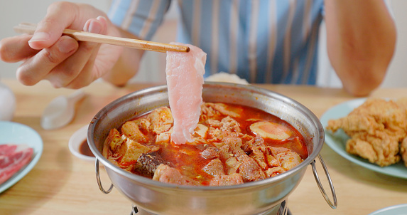 close up asian man is eating spicy hot pot with chopsticks