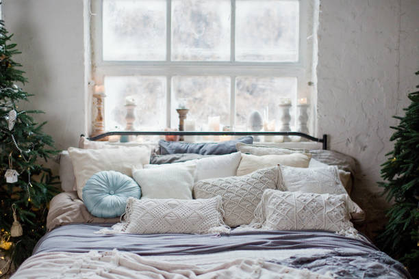 Christmas loft bedroom with big windows, Christmas decorations, Christmas trees and lights. Loft boho interior with Christmas decor