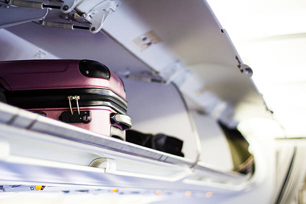 Briefcase in the plane Suitcase in the open log of the airplane cabin passenger cabin stock pictures, royalty-free photos & images