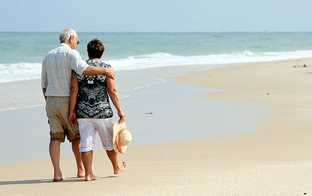 istock Happy senior couple walking together on a beach 179004678