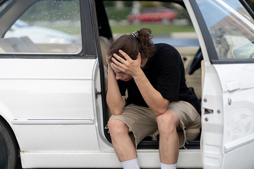 a young male driver feel sad and depressed in the white old car