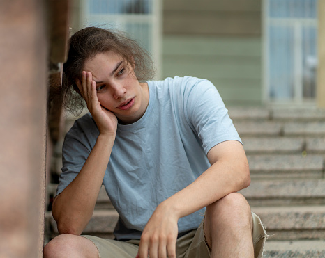 A man sitting on stairs steps holding his head with his hands