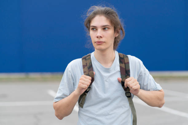 istock young man with long hair standing outdoors with a backpack 1790055164