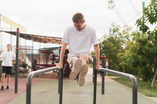 A Determined Athlete doing power workout in the park, push ups on the metal bars