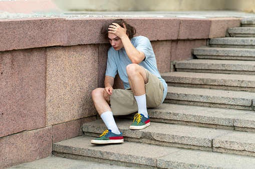 A man sitting on stairs steps holding his head with his hands