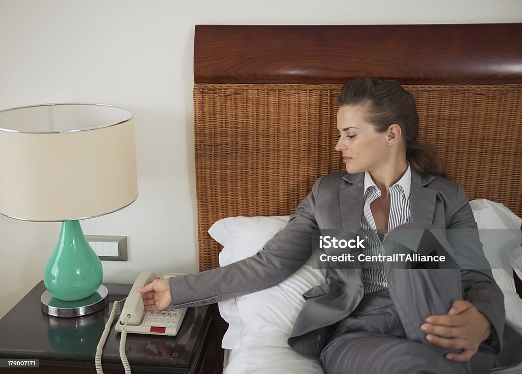 Donna d'affari di rispondere a telefono sul letto nella camera d'albergo - Foto stock royalty-free di Adulto