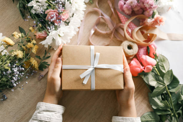 istock Gift box in hands with flowers at home 1790109791