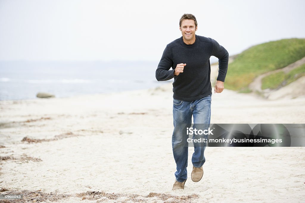Hombre corriendo en la playa Sonriendo - Foto de stock de Hombres libre de derechos