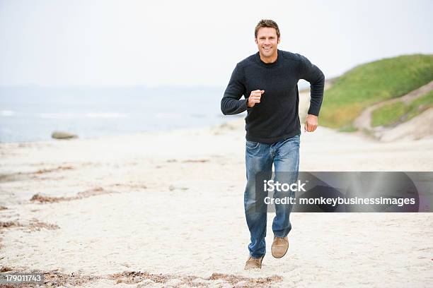 Hombre Corriendo En La Playa Sonriendo Foto de stock y más banco de imágenes de Hombres - Hombres, Acercarse, Correr