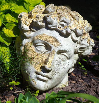 Closeup of decaying replica  Roman modelled statue head in garden