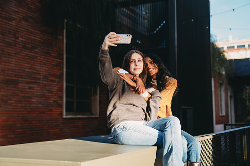 Two friends are taking a selfie in the city. They are having fun together.