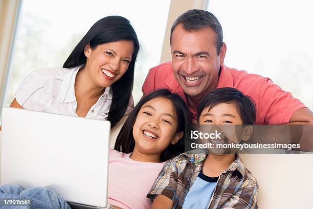 Familia En La Sala De Estar Con Portátil Sonriendo Foto de stock y más banco de imágenes de Familia - Familia, Ordenador portátil, De ascendencia europea