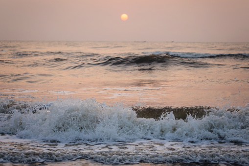 A sunrise over the Bay of Bengal with waves crashing.
