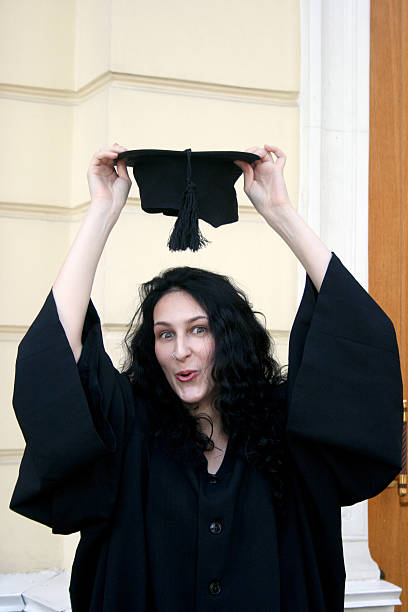 istock Young student in gown near the university trying on cap 179016683