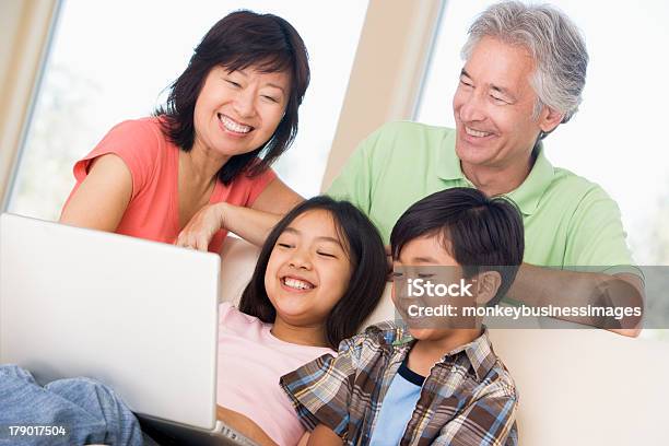 Photo libre de droit de Couple Avec Deux Enfants À Laide Dun Ordinateur Portable Dans La Salle De Séjour banque d'images et plus d'images libres de droit de Adulte