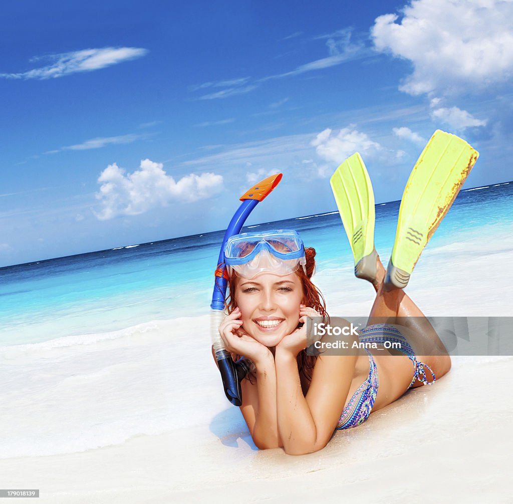 Happy diver woman Happy diver woman lying down on beautiful sandy beach, wearing goggles, tube and flippers, having fun on summertime resort, active lifestyle, water discovery concept Activity Stock Photo