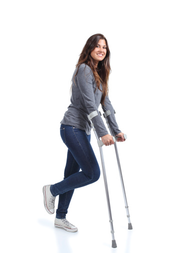 Woman walking with crutches on a white isolated background