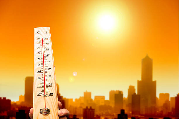 heatwave na cidade e mão mostrando o termómetro - fotografia de stock