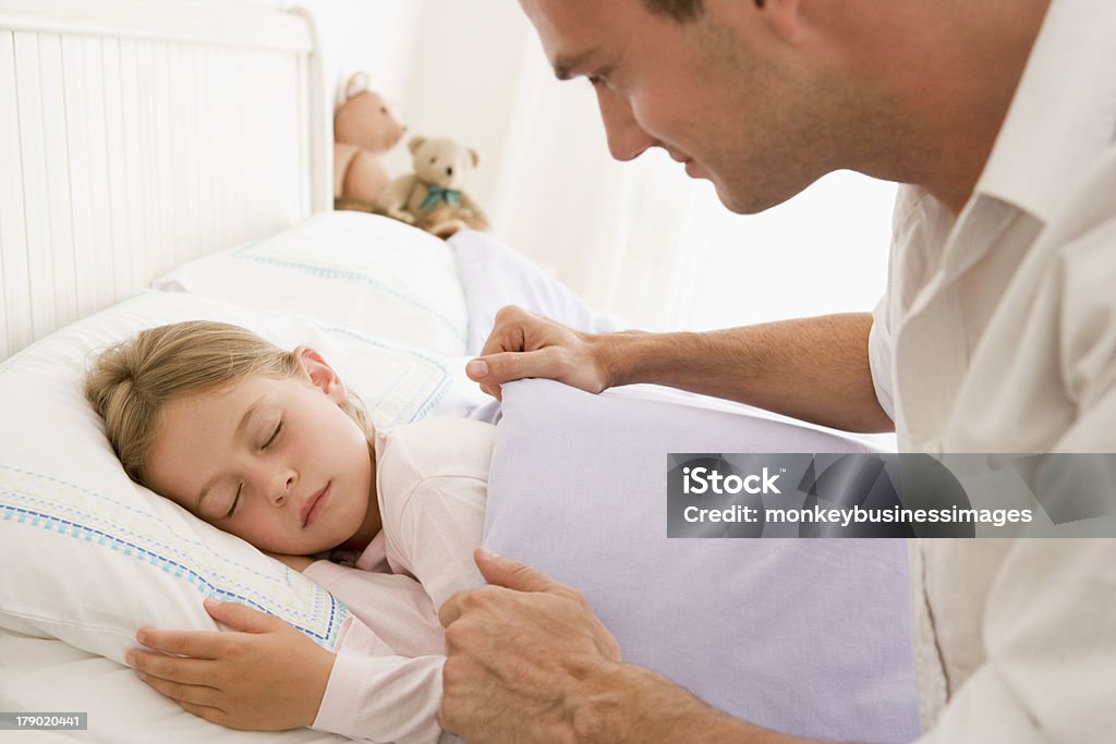 Man waking young girl in bed smiling Man waking young girl in bed smiling looking at daughter 20-29 Years Stock Photo