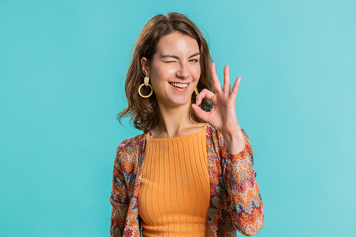 Okay. Joyful happy young woman looking approvingly at camera showing approve feedback gesture like Ok sign positive something good. Pretty girl isolated on blue background. People sincere emotion